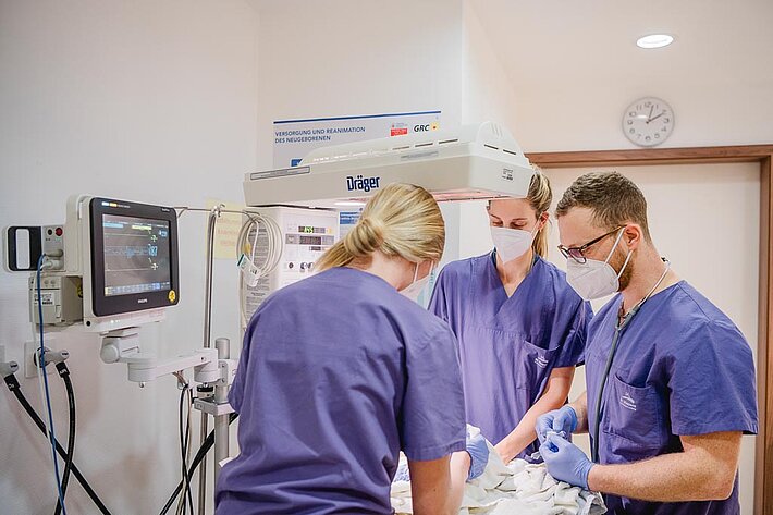 Neonatologen und Kinderkrankenschwestern versorgen ein Frühgeborenes im Inkubator.