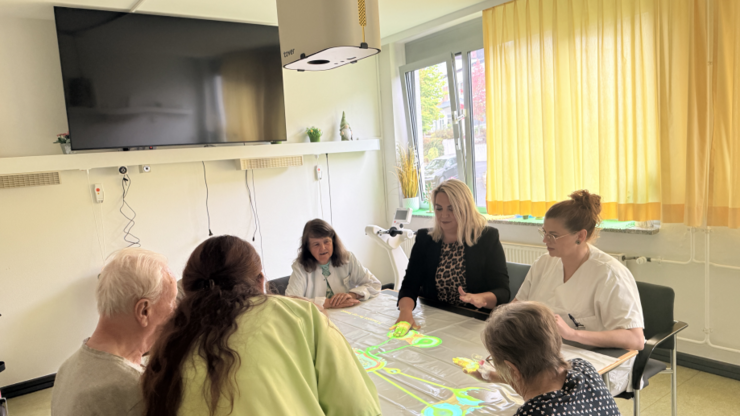 Sechs Personen sitzen um einen Tisch und spielen ein aktivierendes Spiel mit der Tovertafel