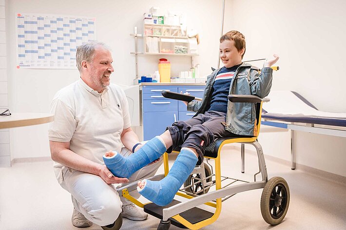 Arzt und junger Patient im Rollstuhl im Gespräch